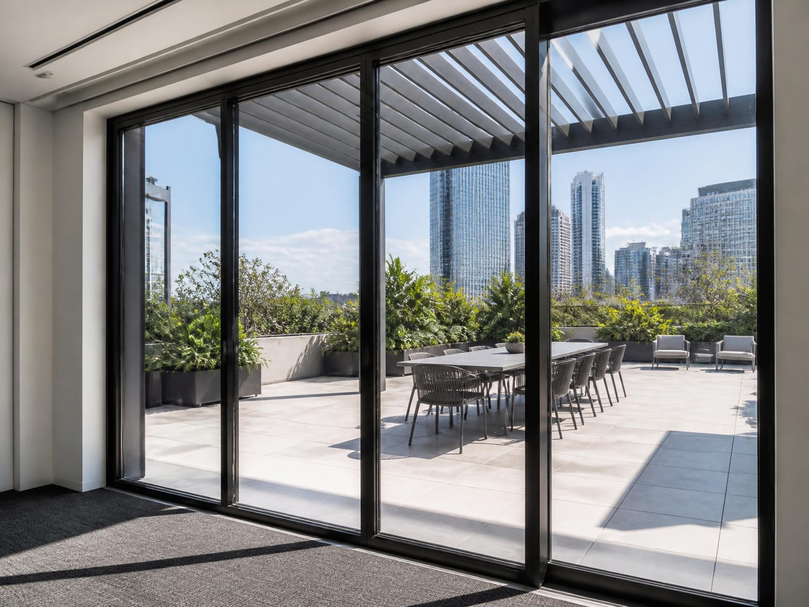 Portas de correr em alumínio com perfis finos abrindo para terraço corporativo